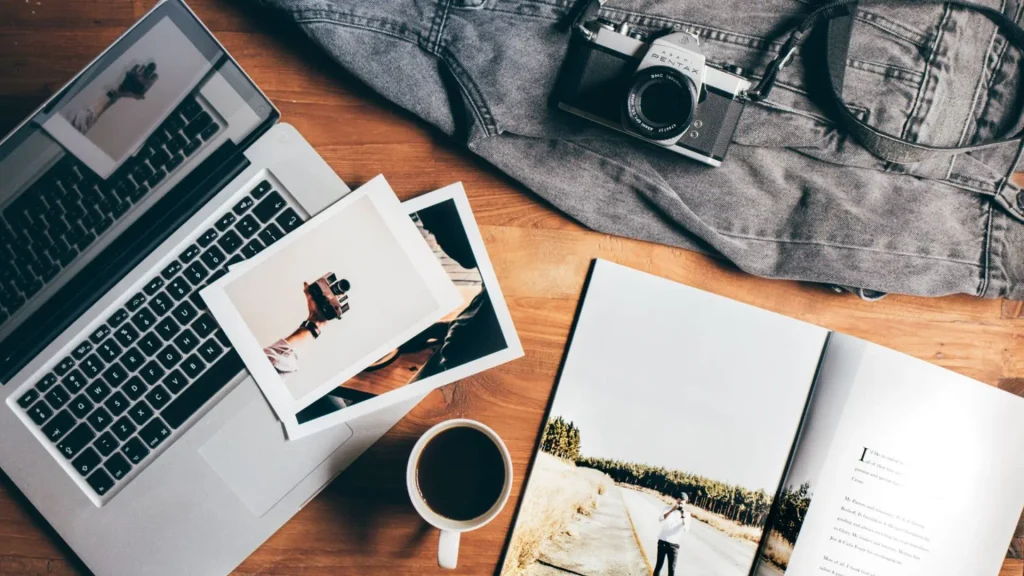 Laptop, printed photos and coffee on a wooden desk, a setup for remote sessions from anywhere Online Therapy for Travellers