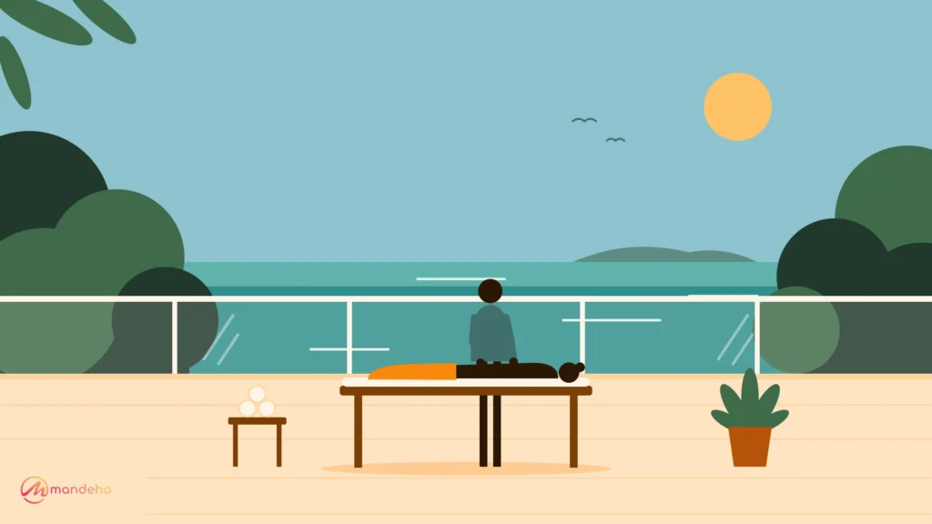 A woman receives a relaxing massage from a therapist on an open-air cliffside spa deck with glass railings, lush greenery and a turquoise ocean view, capturing the calm of wellness tourism.