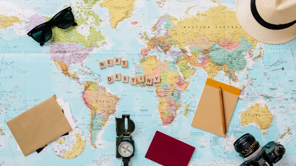 Travel planning flat lay with world map, passport, notebook and compass