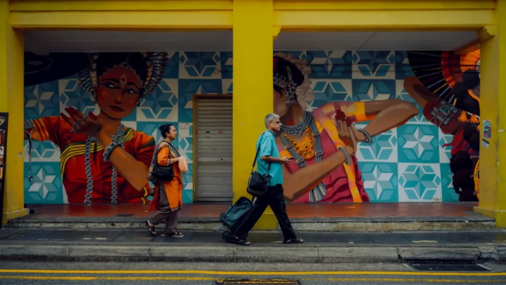 Indian travelers walking past a vibrant cultural mural in an unfamiliar foreign street