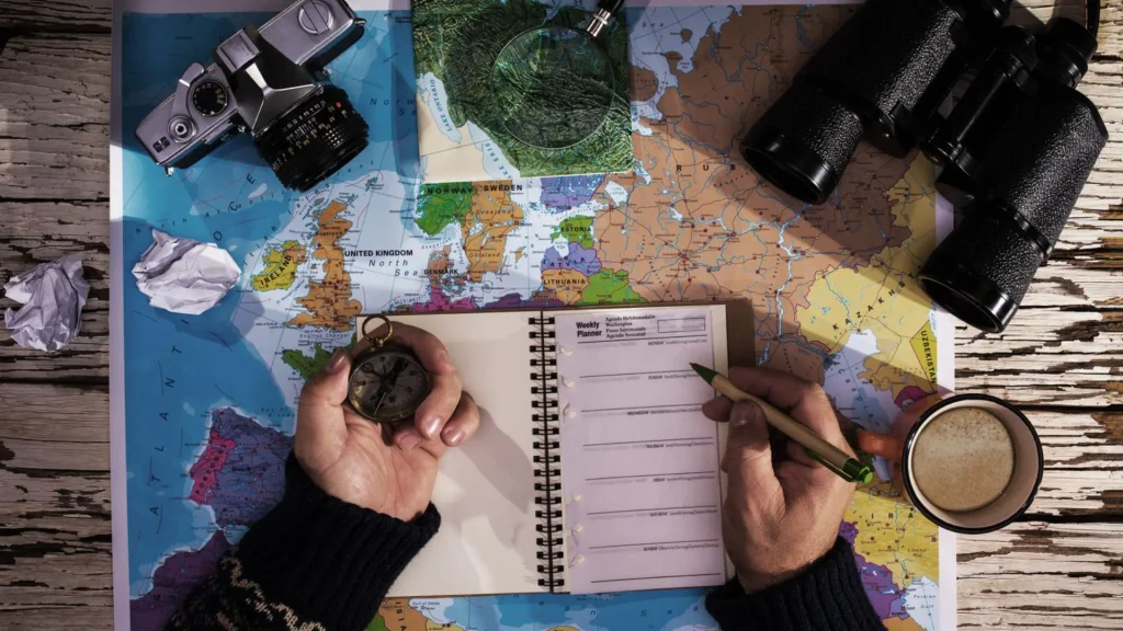 Person planning a mindful trip with a map, compass and weekly planner